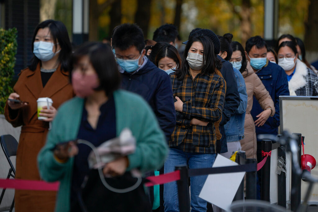 People wearing face masks line up for their routine COVID-19 throat swabs at a coronavirus testing site in Beijing, Tuesday, Nov. 1, 2022. (AP Photo/Andy Wong)