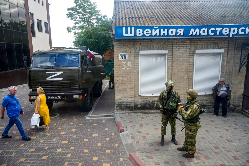 Russian soldiers guard an office for Russian citizenship applications as their military truck is parked nearby, in Melitopol, south Ukraine, on July 14, 2022. (AP Photo, File)