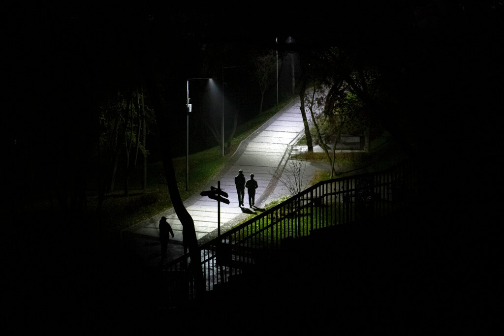 People walk in a park during a blackout in Kyiv, Ukraine, Sunday, Nov. 6, 2022. (AP Photo/Andrew Kravchenko)