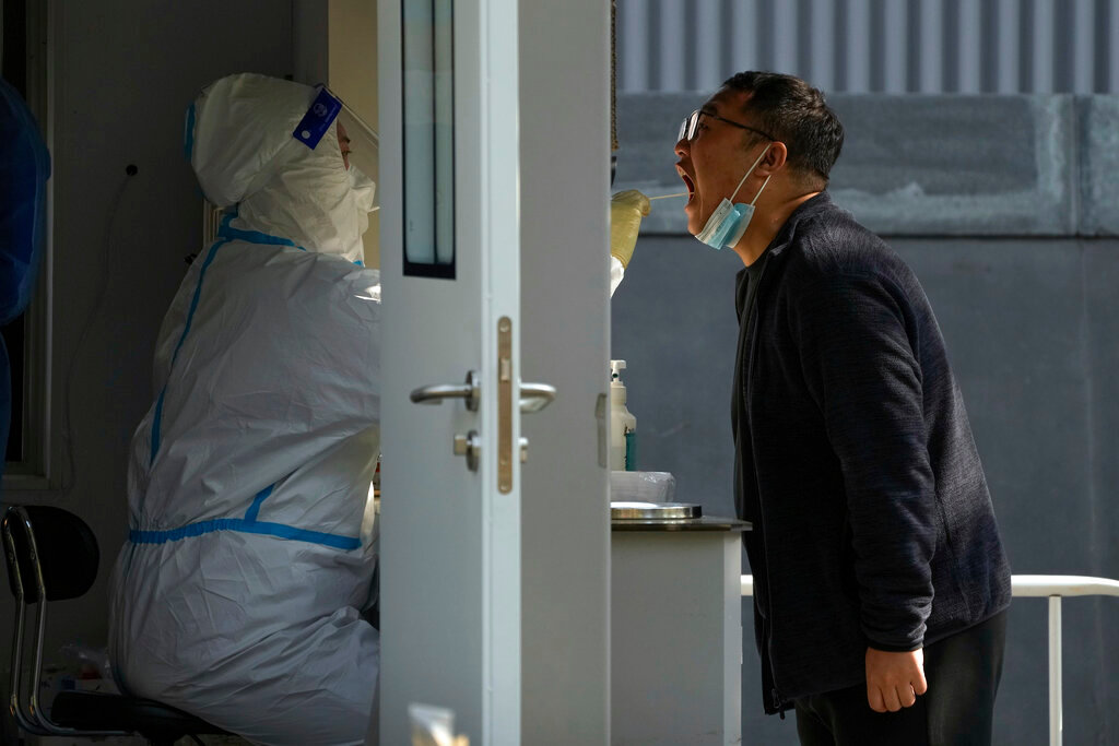 A worker in protective suit collects a sample from a man at a coronavirus testing site in Beijing, Tuesday, Nov. 8, 2022. (AP Photo/Andy Wong)