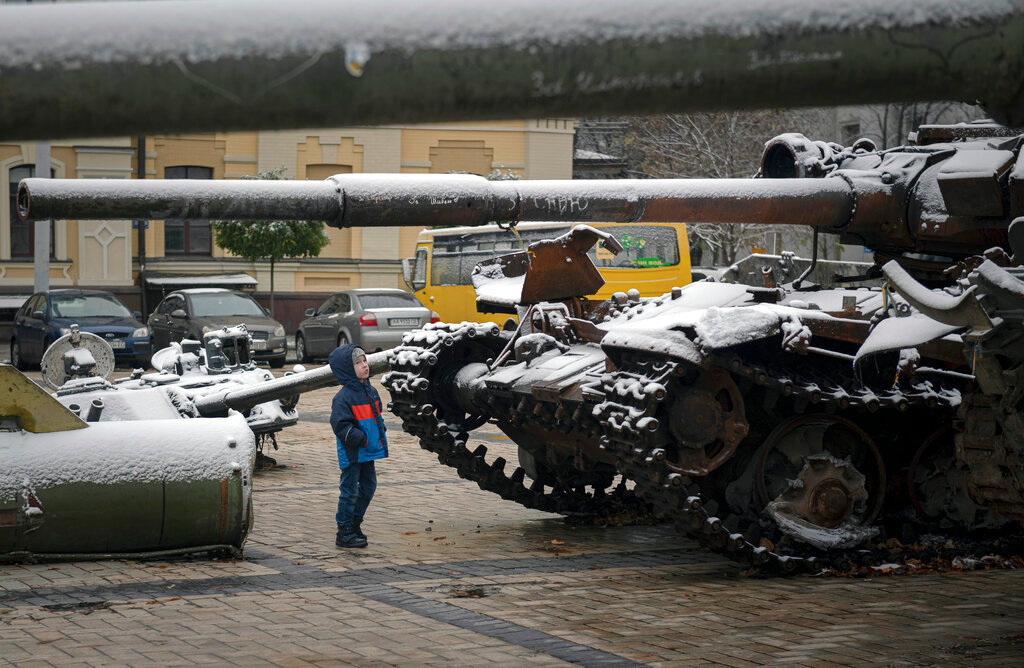 A child looks at a display of destroyed Russian tanks and armoured vehicles after snowfall in downtown Kyiv, Ukraine, Thursday, Nov. 17, 2022. (AP Photo/Andrew Kravchenko)