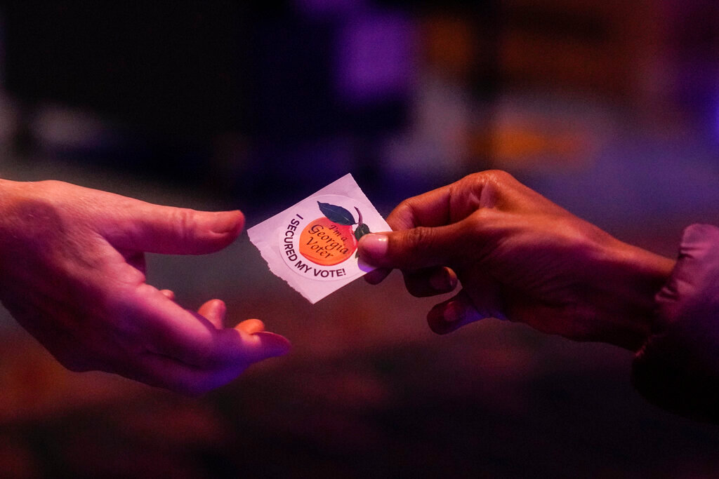 A poll worker hands a voter a sticker on Election Day, Tuesday, Nov. 8, 2022, in Atlanta. (AP Photo/Brynn Anderson)