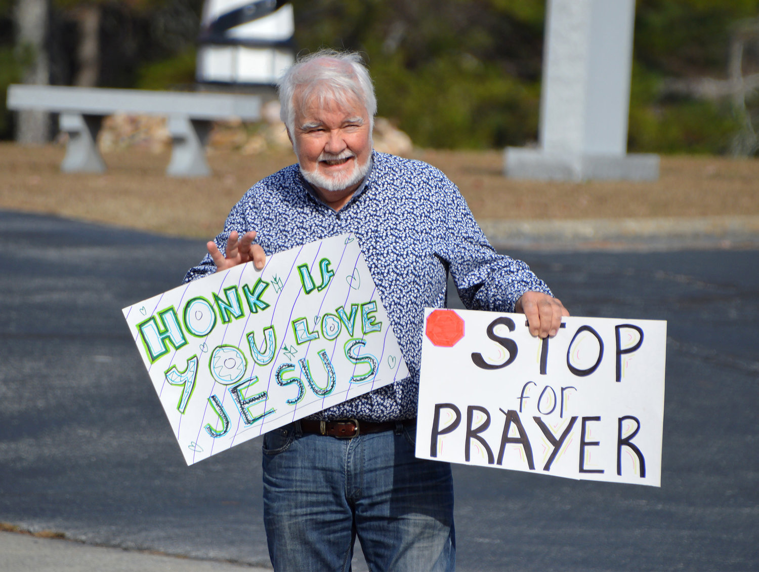 Bill Lloyd waves to a honking motorist while holding signs encouraging people to pull into New Hope First Baptist Church for drive-thru prayer on Saturday, Nov. 19, 2022, in Dallas, Ga. (Index/Henry Durand)