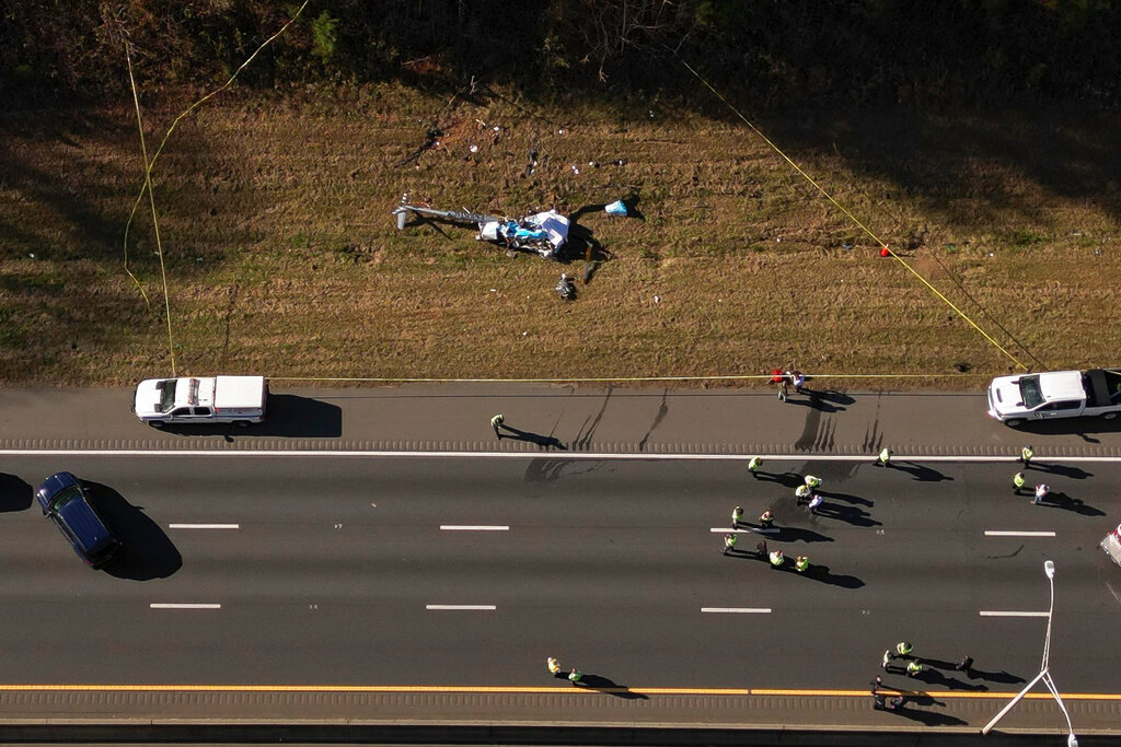 In this image take with a drone, emergency personnel work at the scene of a helicopter crash on the side of Interstate 77 South in Charlotte, N.C.,  Tuesday, Nov. 22, 2022. Authorities said two people died. ( (Alex Slitz/The Charlotte Observer via AP)