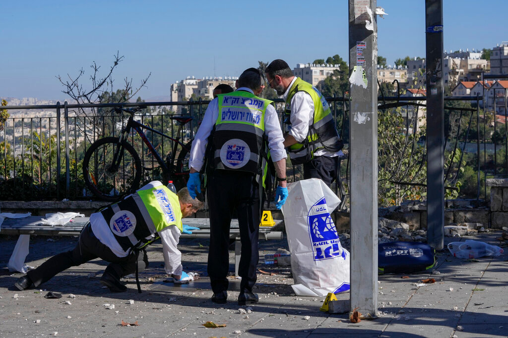 Members of Zaka Rescue and Recovery team clean blood from the scene of an explosion at a bus stop in Jerusalem, Wednesday, Nov. 23, 2022. Two blasts have gone off near bus stops in Jerusalem, killing one person and injuring at least 14, in what Israeli police said were suspected attacks by Palestinians.  (AP Photo/Maya Alleruzzo)