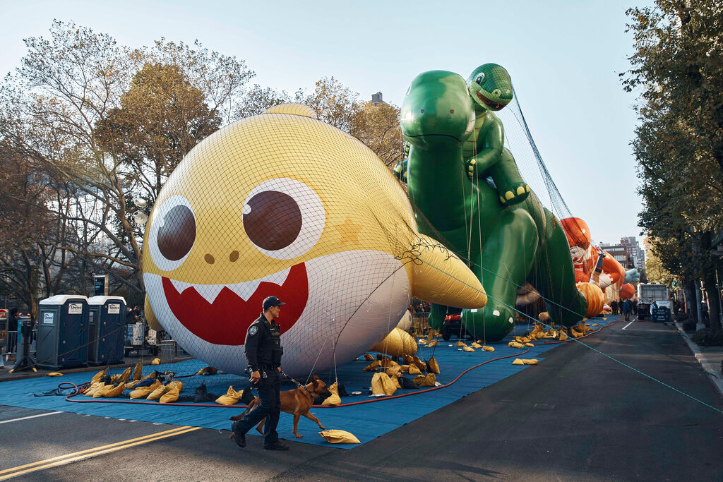 Police walk by inflated helium balloons of Baby Shark and Sinclair's Dino on Wednesday, Nov. 23, 2022, in New York, as the balloons are readied for the Macy's Thanksgiving Day Parade on Thursday. (AP Photo/Andres Kudacki)