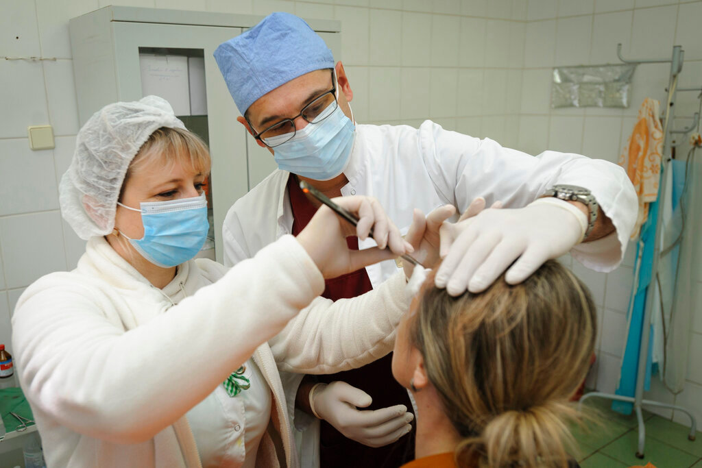 Ukrainian doctor Oleh Duda, center, examines a patient at the hospital in the western city of Lviv, Ukraine, on Saturday, Nov. 26, 2022. (AP Photo/Mykola Tys)
