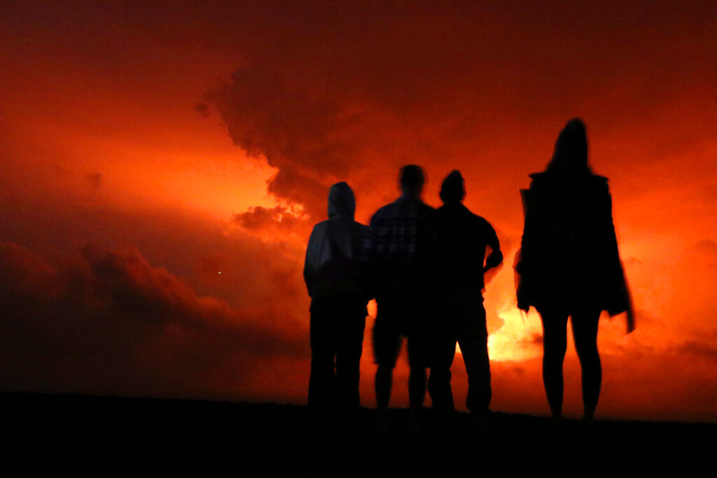 People watch the glow from lava erupting from Hawaii's Mauna Loa volcano, Monday, Nov. 28, 2022 in Hilo, Hawaii. (AP Photo/Caleb Jones)