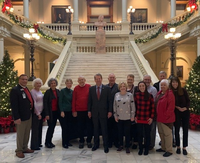 Georgia Gov. Brian Kemp, center, poses with visitors during a 2021 Prayer Tour of the Georgia state Capitol on Dec. 8, 2021.