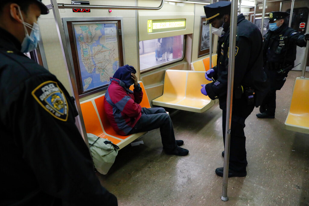 New York police officers wake up sleeping passengers and direct them to the exits at the 207th Street station on the A train, April 30, 2020, in the Manhattan borough of New York. (AP Photo/John Minchillo, File)