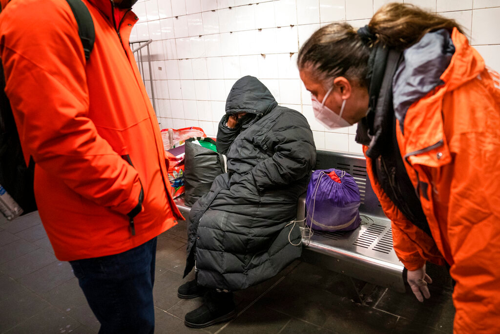 Homeless outreach personnel interact with a person sleeping on a bench in the Manhattan subway system, Feb. 21, 2022, in New York.  (AP Photo/John Minchillo, File)