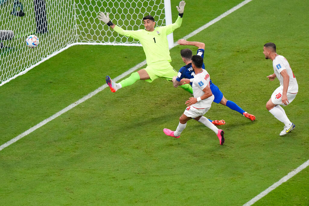 Christian Pulisic of the United States scores his side's opening goal past Iranian goalkeeper Alireza Beiranvand during the first half of their World Cup group B match in Doha, Qatar, Tuesday, Nov. 29, 2022. (AP Photo/Luca Bruno)