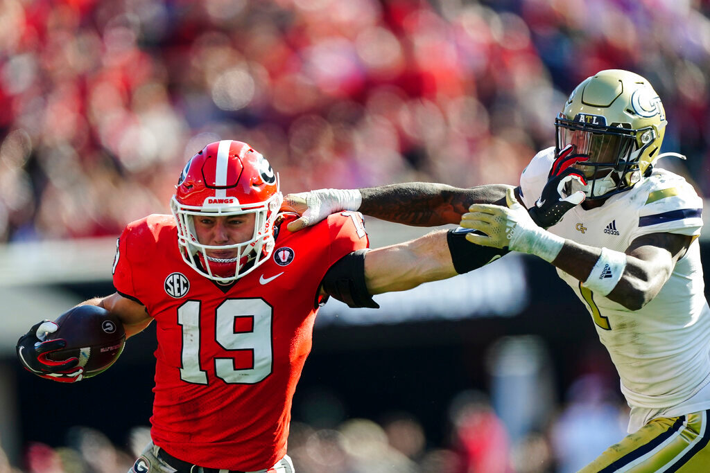 Georgia tight end Brock Bowers (19) fends off Georgia Tech defensive back Zamari Walton as he runs after a catch during the first half Saturday, Nov. 26, 2022, in Athens, Ga. Bowers was called for a face masking penalty. (AP Photo/John Bazemore)