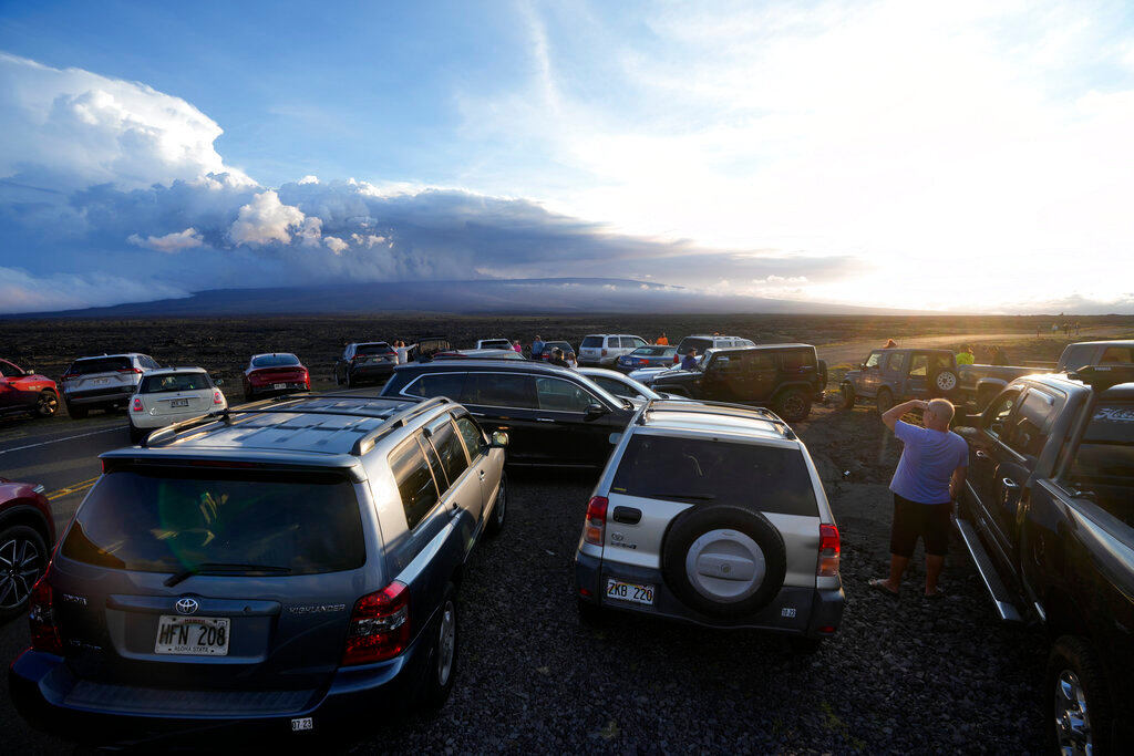 An overflow of cars sit in a parking lot near the Mauna Loa volcano as it erupts Wednesday, Nov. 30, 2022, near Hilo, Hawaii. (AP Photo/Gregory Bull)
