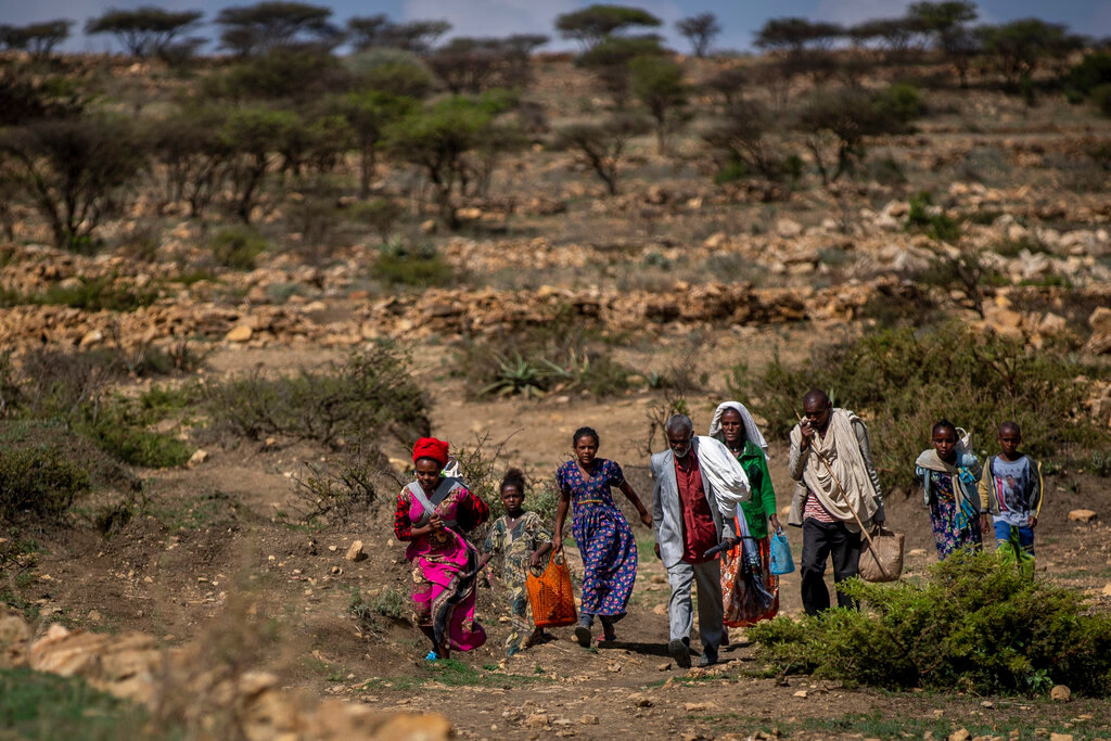 People walk from a rural area towards a nearby town where a food distribution operated by the Relief Society of Tigray was taking place, near the town of Agula, in the Tigray region of northern Ethiopia on May 8, 2021. (AP Photo/Ben Curtis, File)