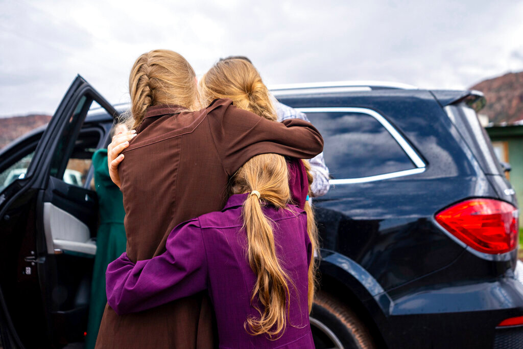Three girls embrace before they are removed from the home of Samuel Bateman, following his arrest in Colorado City, Ariz., on Wednesday, Sept. 14, 2022.  Federal documents released Friday, Dec. 2 show that Bateman, the leader of a small polygamous group near the Arizona-Utah border, had taken at least 20 wives, most of whom were minors, and punished followers who did not treat him as a prophet.  (Trent Nelson/The Salt Lake Tribune via AP, File)