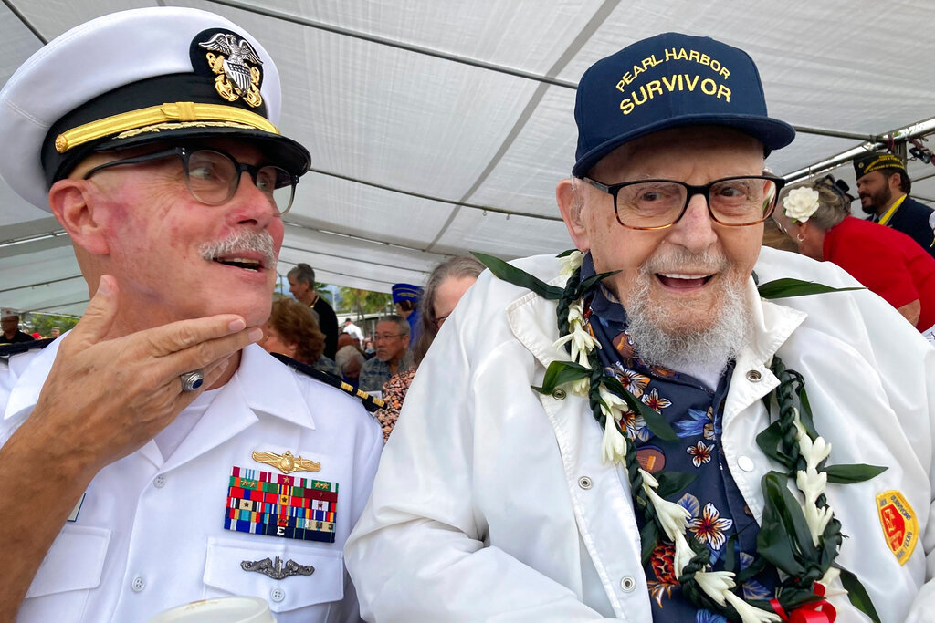 Ira Schab, 102, right, who survived the attack on Pearl Harbor as a sailor on the USS Dobbin, talks with reporters while sitting next to his son, retired Navy Cmdr. Karl Schab, Wednesday, Dec. 7, 2022, in Pearl Harbor, Hawaii. A handful of survivors of the attack on Pearl Harbor gathered at the scene of the Japanese bombing to commemorate those who perished 81 years ago. (AP Photo/Audrey McAvoy)