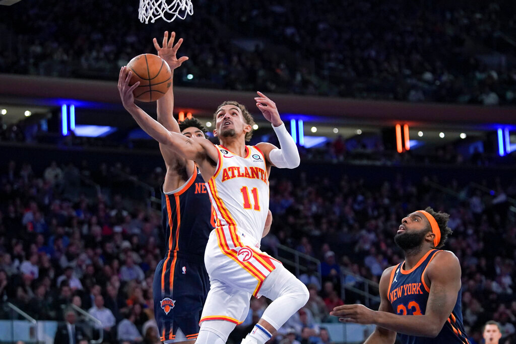 Atlanta Hawks guard Trae Young (11) goes to the basket past New York Knicks center Mitchell Robinson (23) and guard Quentin Grimes during the first half of an NBA basketball game Wednesday, Dec. 7, 2022, at Madison Square Garden in New York. (AP Photo/Mary Altaffer)