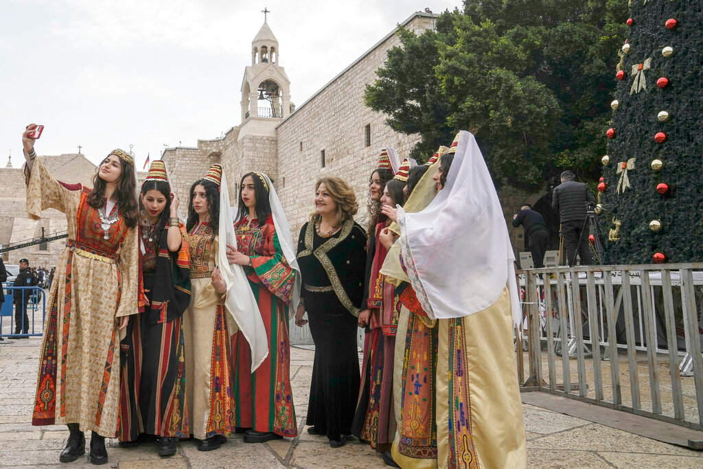 Women pose for a photo as they visit the Church of the Nativity, traditionally believed to be the birthplace of Jesus Christ, in the West Bank town of Bethlehem, Saturday, Dec. 24, 2022. (AP Photo/Mahmoud Illean)