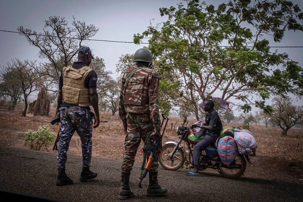 A police officer and a soldier from Benin stop a motorcyclist at a checkpoint outside Porga, Benin, March 26, 2022. (AP Photo/Marco Simoncelli, File)