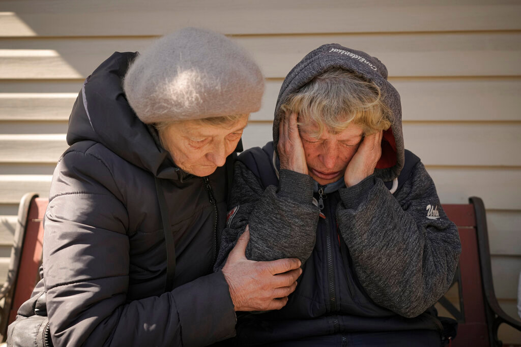 A neighbor comforts Natalia Vlasenko, whose husband, Pavlo Vlasenko, and grandson, Dmytro Chaplyhin, called Dima, were killed by Russian forces, as she cries in her garden in Bucha, Ukraine, April 4, 2022. (AP Photo/Vadim Ghirda, File)