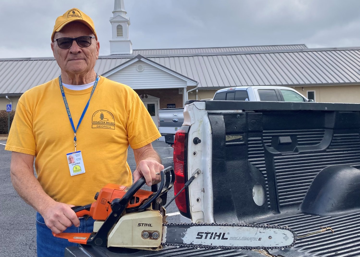 Charles Raburn poses with his chainsaw. The 79-year-old was among those deployed to Griffin to help cleanup tornado damage last week.