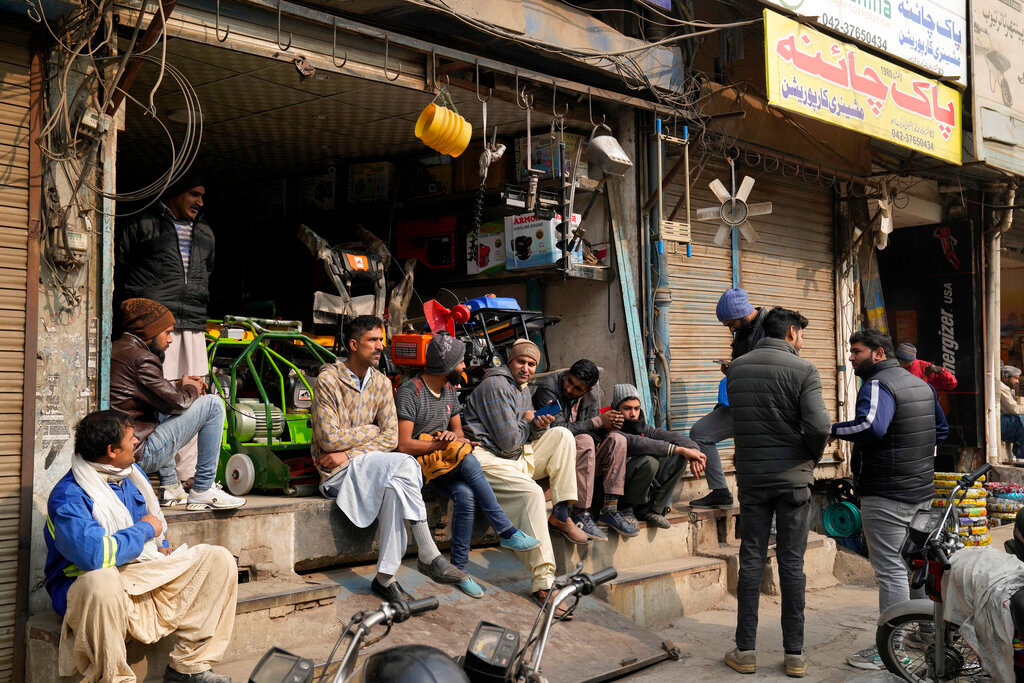 Shopkeepers and workers wait for electric power at a market following a power outage across the country, in Lahore, Pakistan, Monday, Jan. 23, 2023. (AP Photo/K.M. Chaudary)