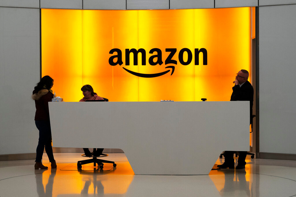 People stand in the lobby for Amazon offices in New York. (AP Photo/Mark Lennihan, File)