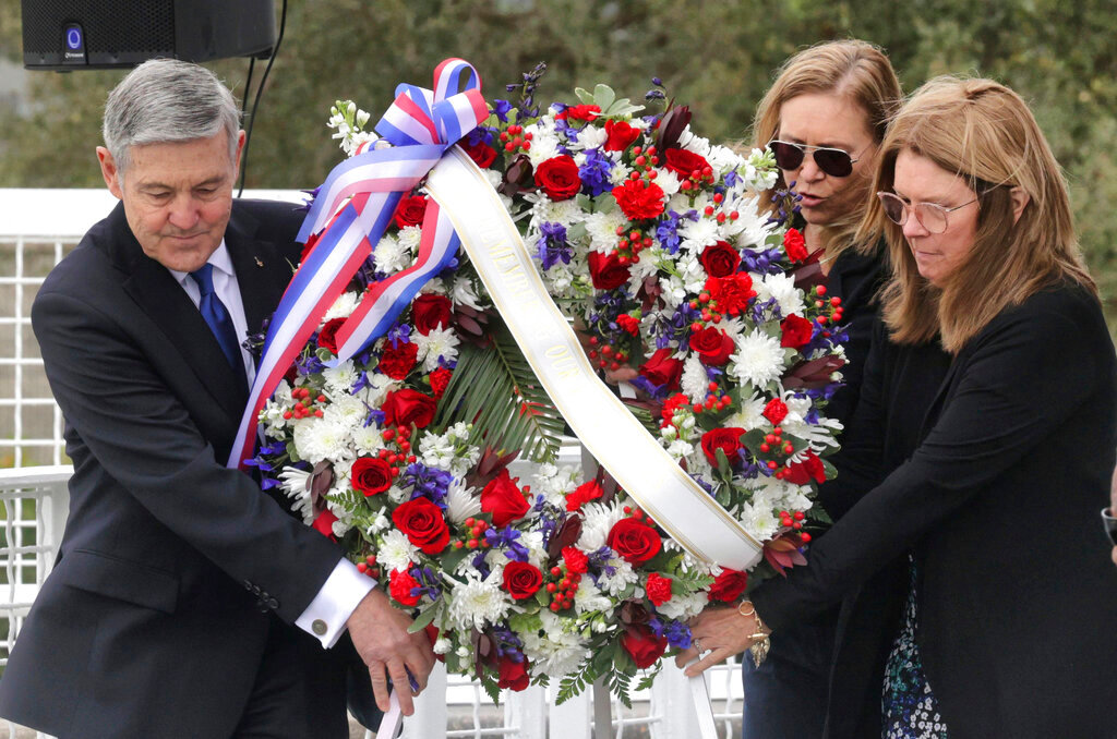A wreath is presented by, from left, Bob Cabana, Associate Administrator of NASA; Janet Petro, NASA Kennedy Space Center director, and Sheryl Chaffee, daughter of Apollo 1 astronaut Roger Chaffee, during NASA's Day of Remembrance ceremony, hosted by the Astronauts Memorial Foundation at Kennedy Space Center Visitor Complex, Thursday, Jan. 26, 2023. (Joe Burbank/Orlando Sentinel via AP)