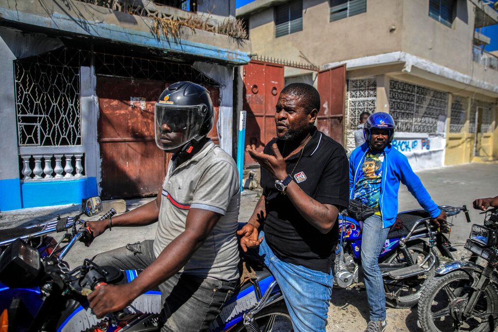 Jimmy Cherizier, the leader of the "G9 et Famille" gang, talks with members of his gang while taking a ride on the back of a motorcycle in his district of Delmas 6 in Port-au-Prince, Haiti, Tuesday, Jan. 24, 2023. (AP Photo/Odelyn Joseph)