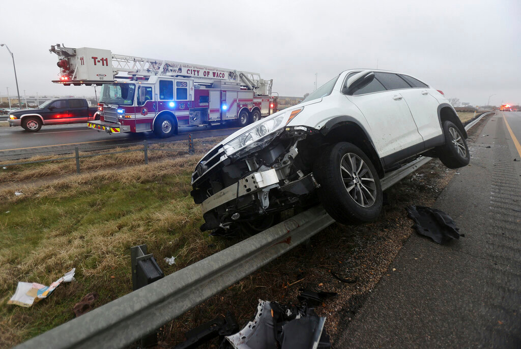 A vehicle rests on a barricade as the driver lost control and slid off Highway 6 on Tuesday Jan. 31, 2023 in Waco, Texas. Winter weather brought ice to Texas and nearby states Tuesday.  (Jerry Larson/Waco Tribune-Herald via AP)