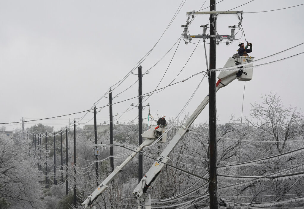 Austin Energy linemen Ken Gray, right, and Chad Sefcik work to restore power on ice-covered lines during a winter storm, Wednesday, Feb. 1, 2023, in Austin, Texas. (Jay Janner/Austin American-Statesman via AP)