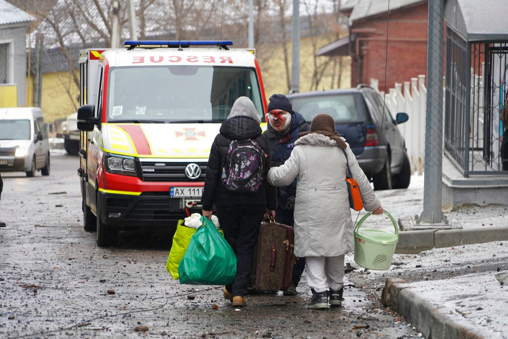 An injured man evacuates with family members from a residential building which was hit by a Russian rocket at the city center of Kharkiv, Ukraine, Sunday, Feb. 5, 2023. (AP Photo/Andrii Marienko)