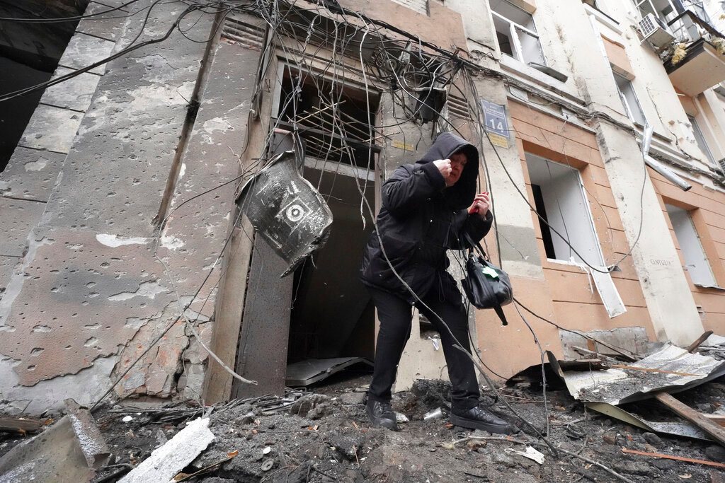 A woman walks out from a residential building which was hit by a Russian rocket, in the city center of Kharkiv, Ukraine, Sunday, Feb. 5, 2023. (AP Photo/Andrii Marienko)