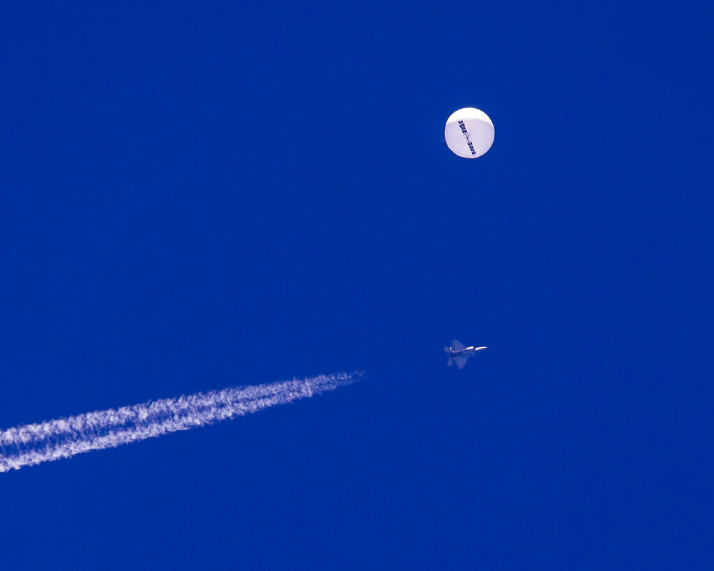 A large balloon drifts above the Atlantic Ocean, just off the coast of South Carolina, with a fighter jet and its contrail seen below it, Saturday, Feb. 4, 2023. (Chad Fish via AP)