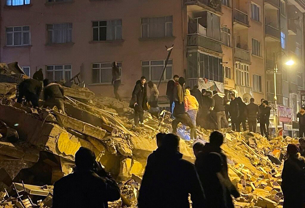 People try to reach trapped residents in a collapsed building in Pazarcik, in Kahramanmaras province, southern Turkey, early Monday, Feb. 6, 2023. (Depo Photos via AP)