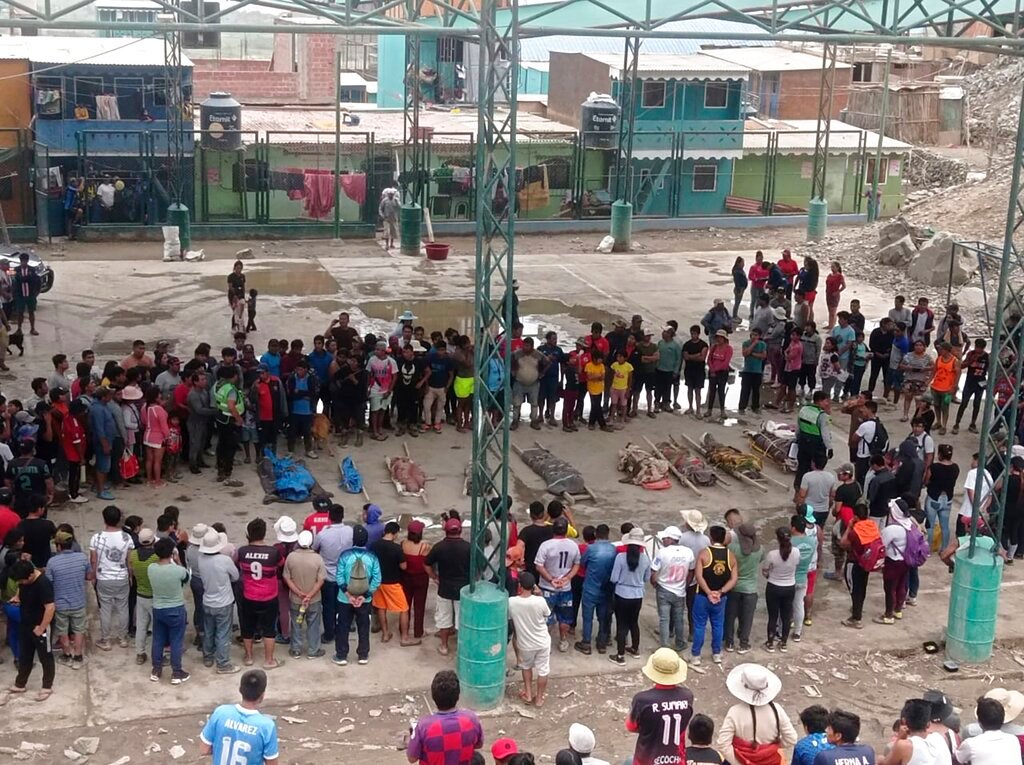 Residents stand around the bodies of persons who perished in recent landslides in Camana, Peru, Monday, Feb. 6, 2023. (AP Photo/Ever Chambi)