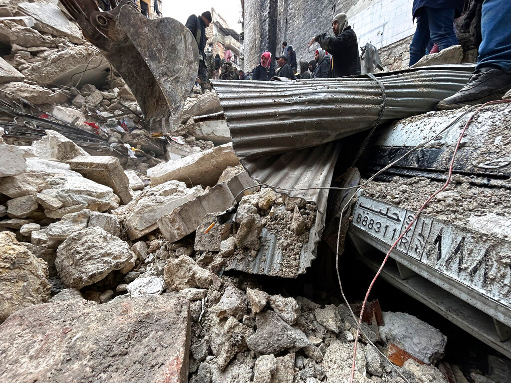Syrian Civil Defense workers and security forces search through the wreckage of collapsed buildings in Aleppo, Syria, Monday, Feb. 6, 2023. (AP Photo/Omar Sanadiki)