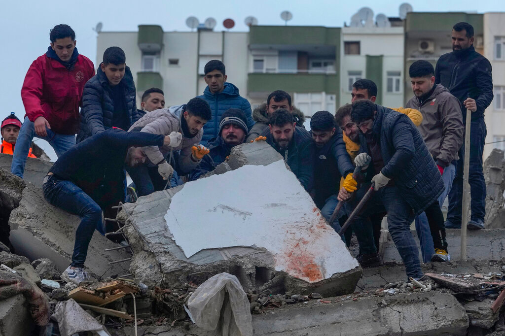 Men search for survivors among the debris in a destroyed building in Adana, Turkey, Monday, Feb. 6, 2023. (AP Photo/Khalil Hamra)