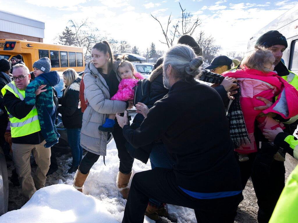 Parents and their children are loaded onto a warming bus as they wait for news after a bus crashed into a day care centre in Laval, Quebec, on Wednesday, Feb. 8, 2023. (Ryan Remiorz/The Canadian Press via AP)