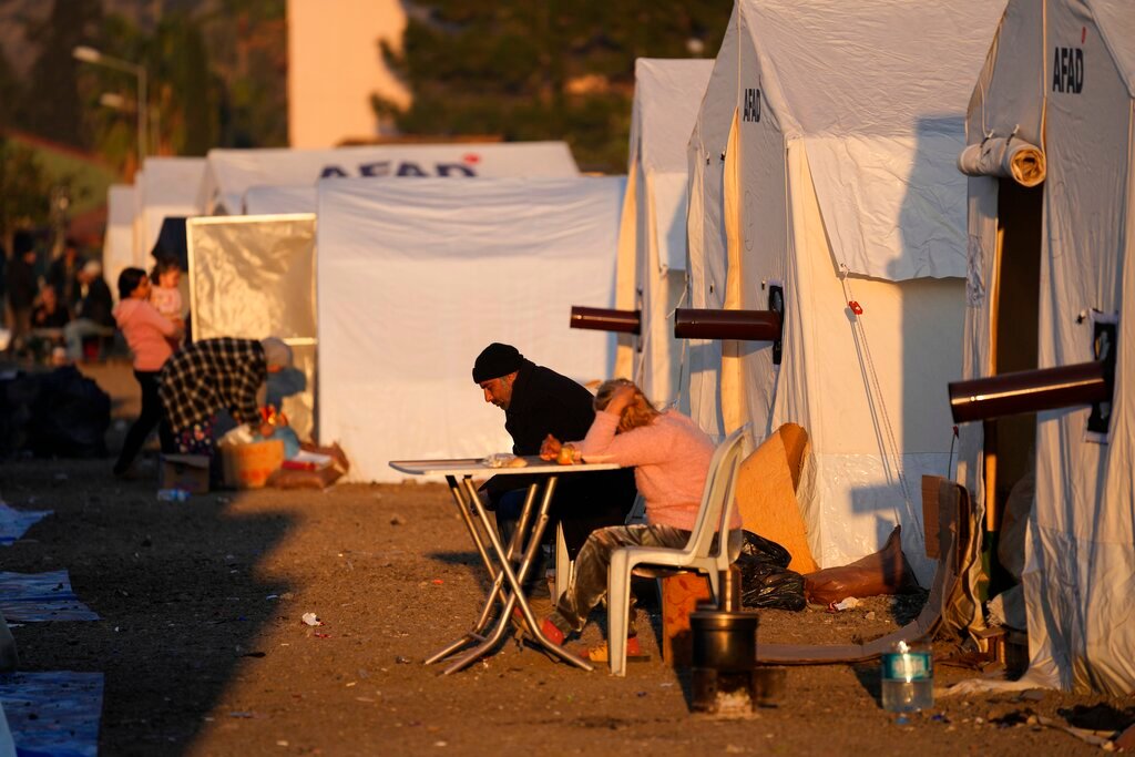 People who lost their houses in the earthquake sit outside their tents at a makeshift camp in Iskenderun, southern Turkey, Tuesday, Feb. 14, 2023. (AP Photo/Hussein Malla)