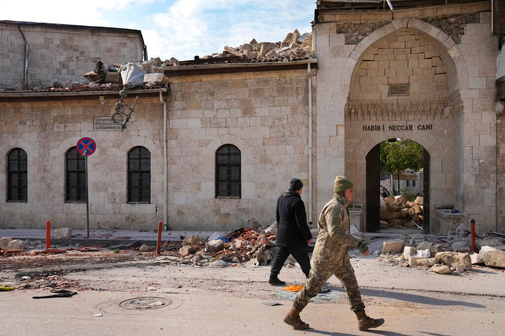 A Turkish soldier walks past the main entrance of the historic Habib Najjar mosque, which was destroyed by a devastating earthquake, in the old city of Antakya, Turkey, Saturday, Feb. 11, 2023. (AP Photo/Hussein Malla)