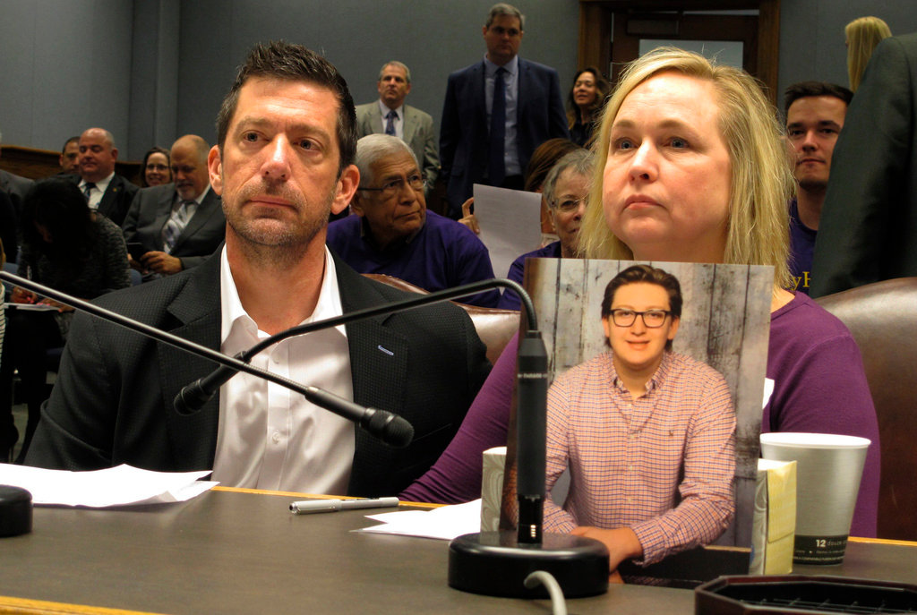 Stephen and Rae Ann Gruver sit in a House committee room behind a photo of their son, 18-year-old Maxwell Gruver, a Louisiana State University freshman who died with a blood-alcohol content six times higher than the legal limit for driving in what authorities say was a hazing incident, in Baton Rouge, La., on March 21, 2018. (AP Photo/Melinda Deslatte, File)