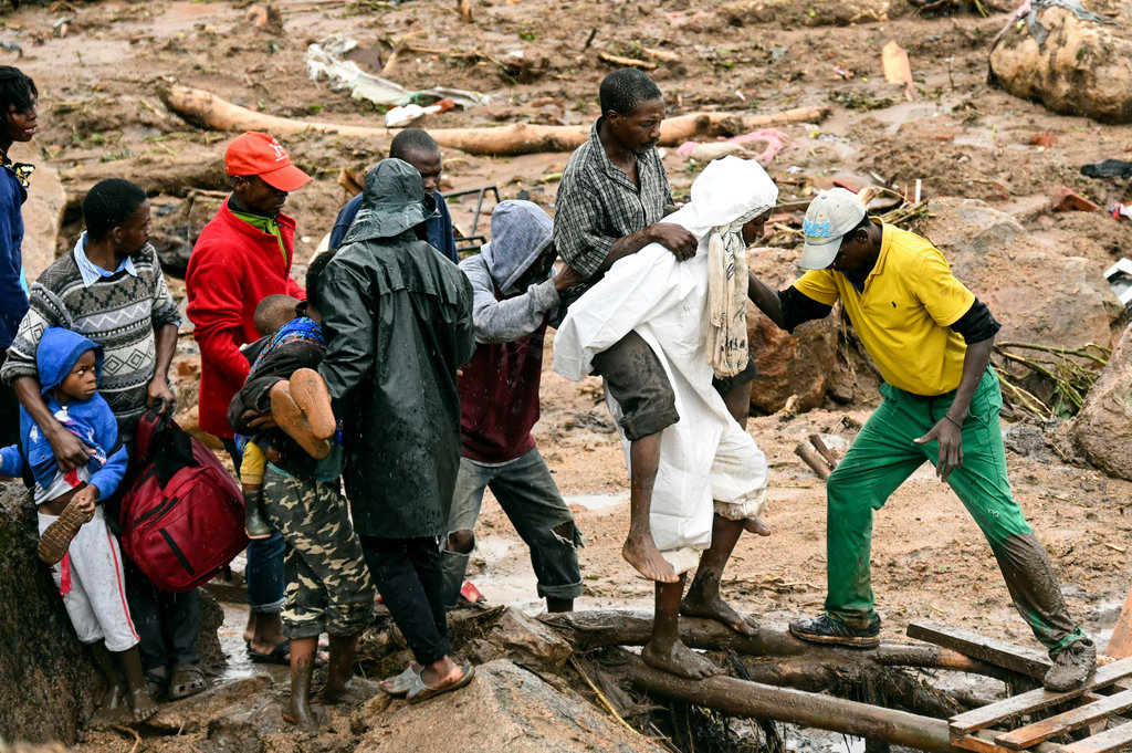 An injured man IS helped across a flooded area in Blantyre, Malawi, Monday, March 13, 2023. (AP Photo/Thoko Chikondi)