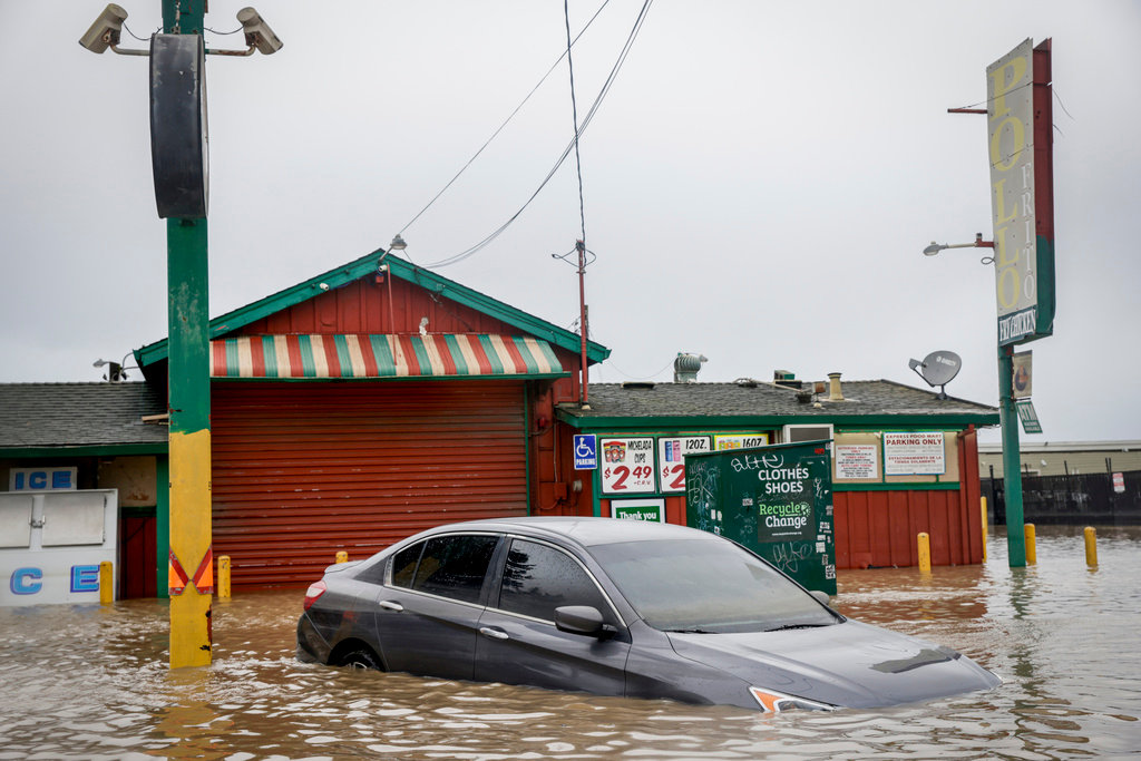 Floodwater from a breached levee submerges cars and floods businesses on Salinas Road in Pajaro, Calif. on Tuesday, March 14, 2023. (Brontë Wittpenn/San Francisco Chronicle via AP)