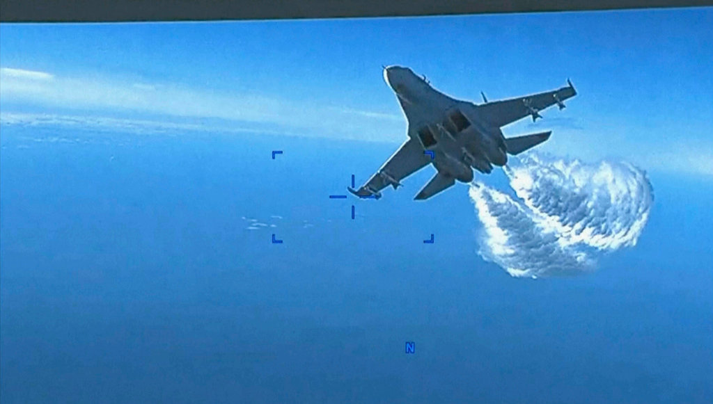 This photo taken from video released on Thursday, March 16, 2023, shows a Russian Su-27 approaching the back of the MQ-9 drone and beginning to release fuel as it passes, over the Black Sea, the Pentagon said. (US Department of Defense via AP)