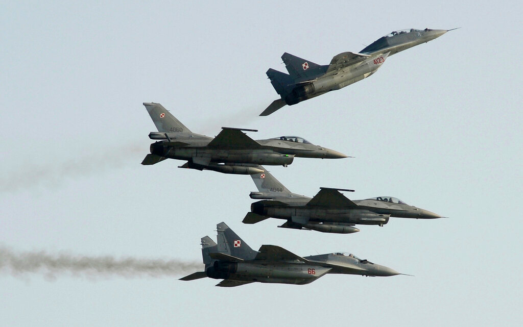 Two Polish Air Force Russian-made MiG-29s fly above and below two Polish Air Force U.S.-made F-16 fighter jets during an air show in Radom, Poland, Aug. 27, 2011. (AP Photo/Alik Keplicz, File)