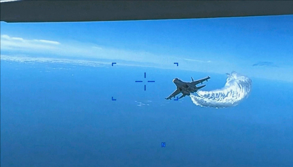This photo taken from video released on Thursday, March 16, 2023, shows a Russian Su-27 approaching the back of the MQ-9 drone and beginning to release fuel as it passes, over the Black Sea, the Pentagon said. (US Department of Defense via AP)