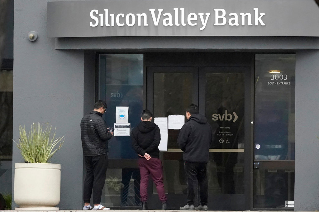 People look at signs posted outside of an entrance to Silicon Valley Bank in Santa Clara, Calif., Friday, March 10, 2023. (AP Photo/Jeff Chiu, File)