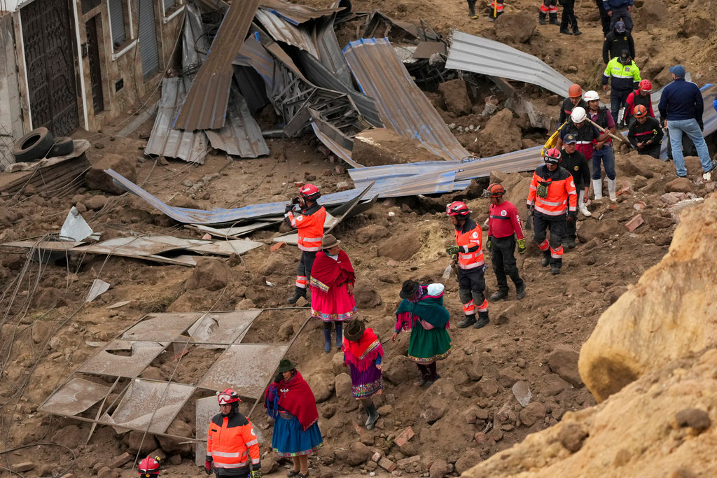 Rescue workers and residents walk amid the debris after a deadly landslide buried dozens of homes in Alausi, Ecuador, Monday, March 27, 2023. (AP Photo/Dolores Ochoa)